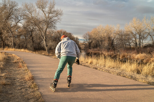senior male  is inline skating on a paved bike trail along Poudre River in Fort Collins, Colorado, fall or winter scenery