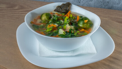 Fresh vegetable soup made of green bean, pea, carrot, potato, red bell pepper, tomato and leek in bowl.