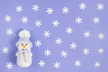 Christmas composition with white snowflakes and a cute snowman on a violet background. Color of the year 2022 Very Peri.