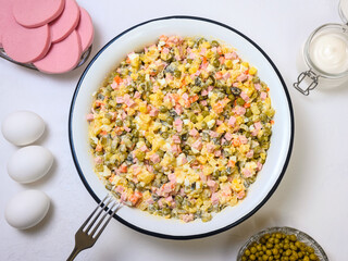 Russian festive salad Olivier in large enamel bowl on white background - flatlay