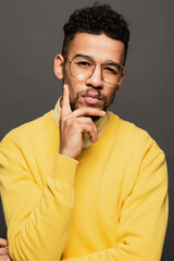 serious african american man in glasses looking at camera isolated on grey.