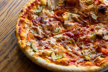 Fresh baked homemade sliced pizza with cheese and ham topping on wooden background.