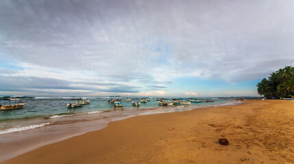 Summer landscape with sea, boats, sandy shore and sky with clouds on the coast of the Indian Ocean in Sri Lanka