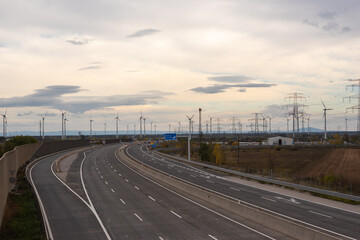 Motorway with turning lane to the energy transition. In the background wind turbines that generate green electricity. Green traffic. Back to nature. No highways. Rethinking for climate change.
