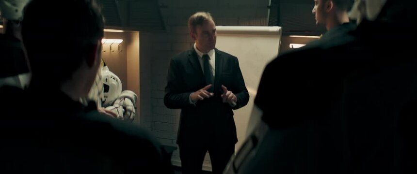 Coach talking to professional ice hockey team players on the locker room before the game. Drawing tactic schemes on a whiteboard. Motivation speech. Shoot with 2x anamorphic lens
