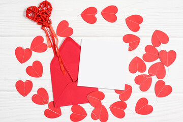 Mockup card with red paper hearts. Valentines invitation card on white wooden background, flat lay, top view, copy space.