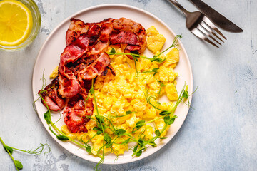 Traditional breakfast scrambled eggs with fried bacon