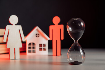 Wooden model of couple, house and hourglass on a table. Divorce and divide concept