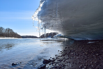 Melting ice hangs over low water on a spring day