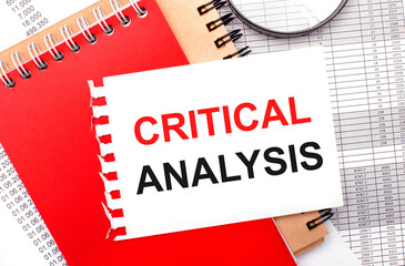 On a light background - reports, a magnifying glass, brown and red notepads, and a white notepad with the text CRITICAL ANALYSIS. Business concept