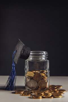 Savings for education concept. Coins in jar with money and graduation hat. Vertical image