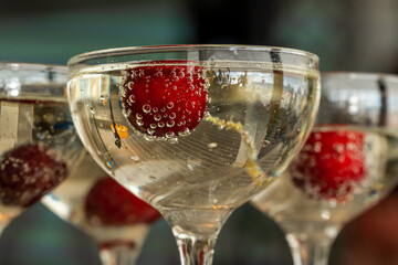 Red cherries in air bubbles float in champagne glasses.