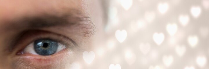 Composite image of close up of a male eye and glowing heart icons on blur background