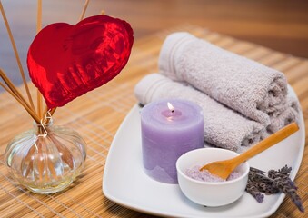 Composite image of red heart shaped foil balloon against towel, candle and bath salt
