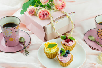 breakfast for two on Valentine's Day. two cups of coffee, a gift for the holiday, a bouquet of roses. background pink textiles.