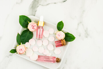 Obraz na płótnie Canvas Top view of cosmetic bottles with rose oil, rose water, rose petals and lovely flowers. the concept of natural self-care. top view.