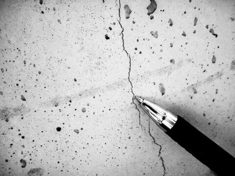 Shallow hairline crack in fresh concrete caused by shrinkage during curing. Pen used for reference.