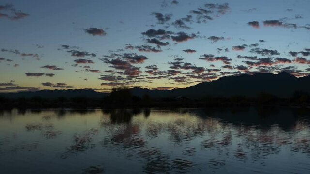 Time lapse of colorful clouds at sunrise over a lake
