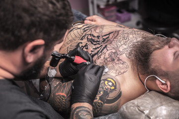 Professional tattooist showing process of making a tattoo in the salon
