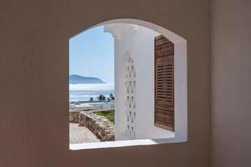 Closed window with wooden bars in an old white wall of a house on the street of Egypt in Sharm El Sheikh