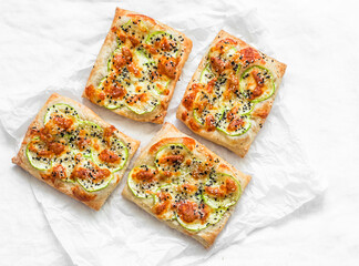 Mini pizza with zucchini, mozzarella and sesame on a light background, top view. Delicious snack, snack, tapas