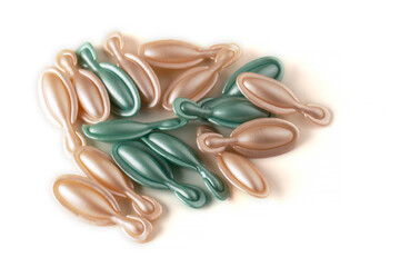 Bicolor face capsules on an isolated white background. Pink and green glitter face serum capsules.