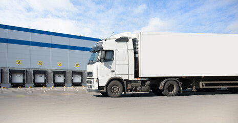 Truck with white cabin in the background of a large distribution warehouse