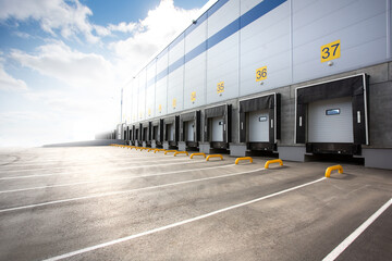 Wall of a huge distribution warehouse with row of loading gates - obrazy, fototapety, plakaty