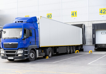 Blue cabin truck under loading at Loading dock of large warehouse