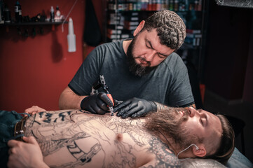 Tattoo artist doing tattoo in tattoo parlour