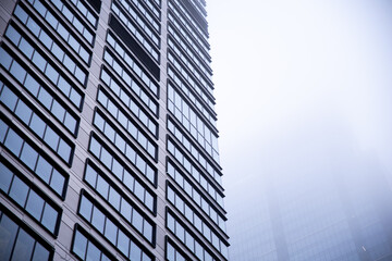 Business center in the tower skyscraper in the financial downtown center of the city in the foggy misty day with cover by clouds tops. Financial business abstract architecture concept.