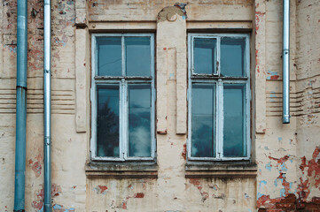 Fototapeta na wymiar ruined and abandoned house exterior. Abandoned house. Broken glass in the window and falling plaster.