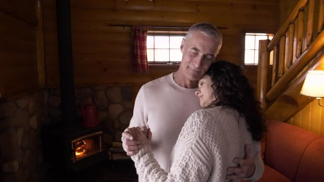 Romantic Couple Dancing At Fireside In Winter Log Cabin