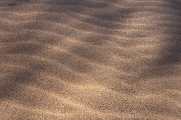 Fototapeta na wymiar Close-up of sand on the beach with wave form produced by the wind