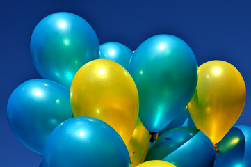blue and yellow metallic balloons in the city festival against deep blue sky 