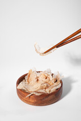 Bonito flakes in a bowl on white background. Katsuobushi is dried, fermented and smoked skipjack tuna fish. Ingredient of traditional Japanese stock or broth Dashi. Vertical, copy space