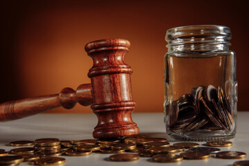 Coins in a glass jar and gavel close-up - obrazy, fototapety, plakaty