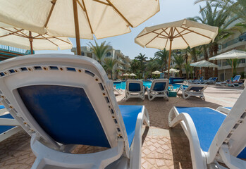 Obraz premium empty beach loungers under palm trees with no people