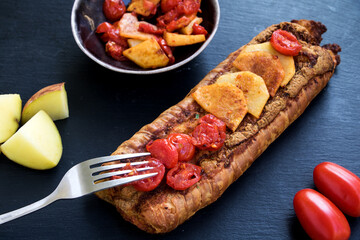würzige kartoffel-tomaten pita mit schüssel und gabel auf dunklen untergrund