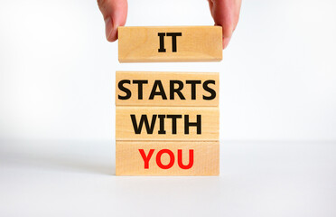 It starts with you symbol. Concept words It starts with you on wooden blocks. Businessman hand. Beautiful white table, white background, copy space. Business and It starts with you concept.