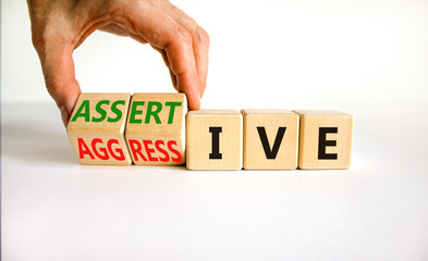 Aggressive or assertive symbol. Businessman turns wooden cubes, changes the word Aggressive to...