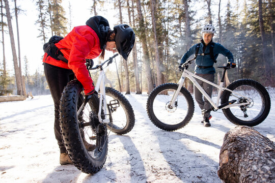 Couple preparing to ride fat bikes in snowy forest