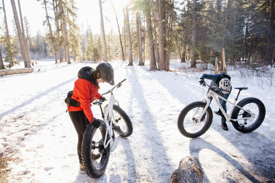 Couple preparing to ride fat bikes in snowy forest