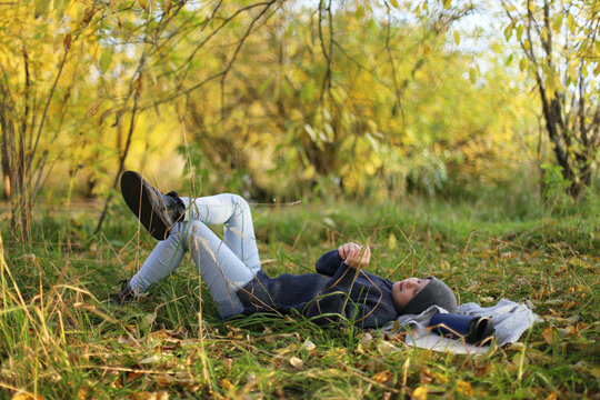 Teenager lies on the grass and rests in the park