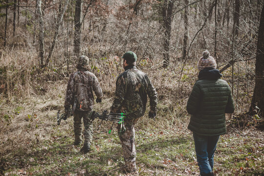 Father and his two teens walking into woods to track deer