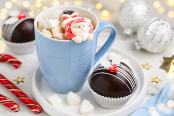 Hot chocolate bombs with marshmallows inside. Christmas dessert for making a drink. A blue mug of...