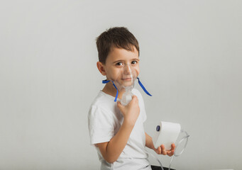 Cute little boy makes inhalation. The child holds an inhaler in his hand and is being treated for a cough. high quality studio photo.