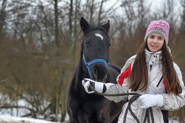 Obraz premium girl in winter with a horse in the paddock