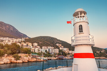 Fototapeta na wymiar Romantic lighthouse at the entrance to the bay and port of Kas fishing and resort town on the Mediterranean coast of Turkey. Sunset and golden hour time