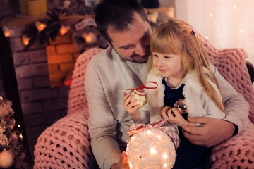 Merry Christmas and Happy Holidays! Dad and daughter decorate the Christmas tree indoors. The morning before Xmas. Portrait loving family close up. - 475603396